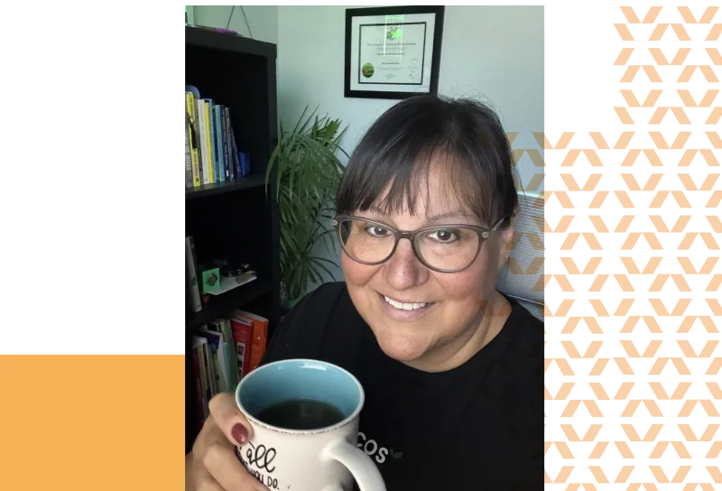Toni holding a cup of coffee and smiling