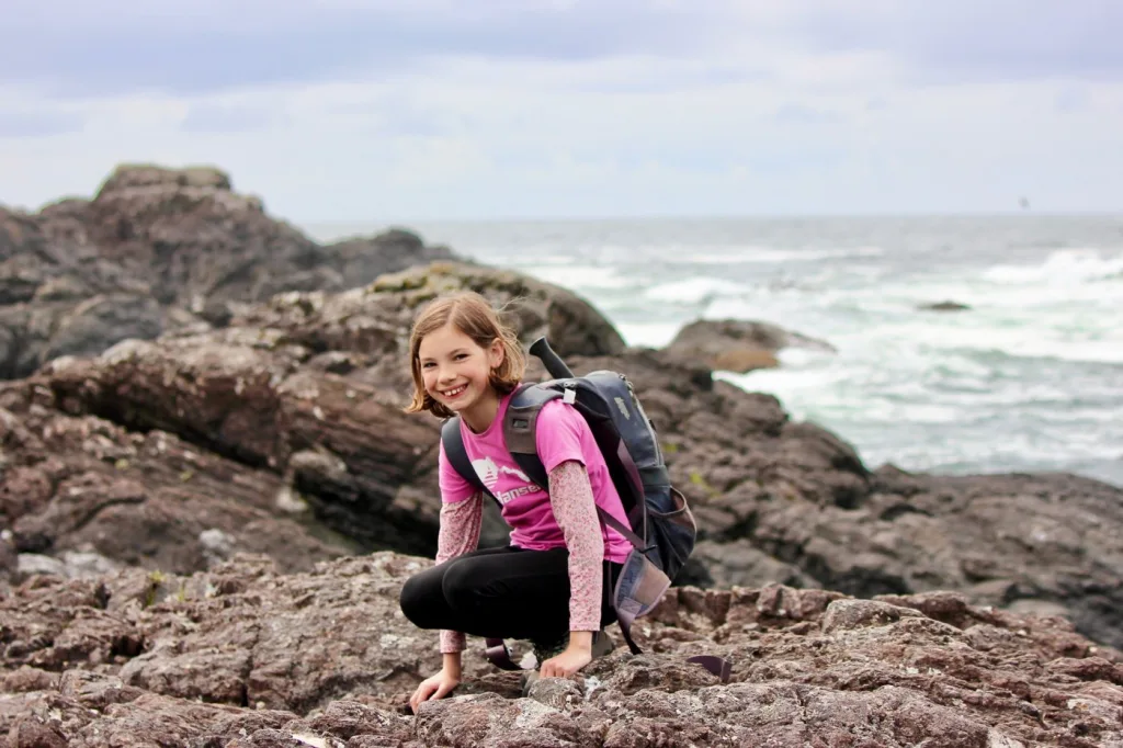 Student with a backpack exploring a rocky shoreline