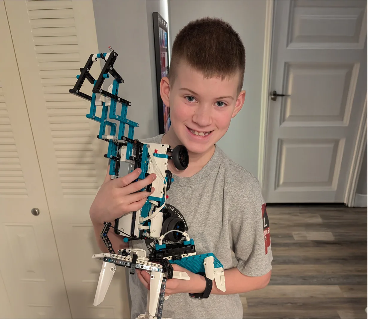 A smiling student holding a robot he built